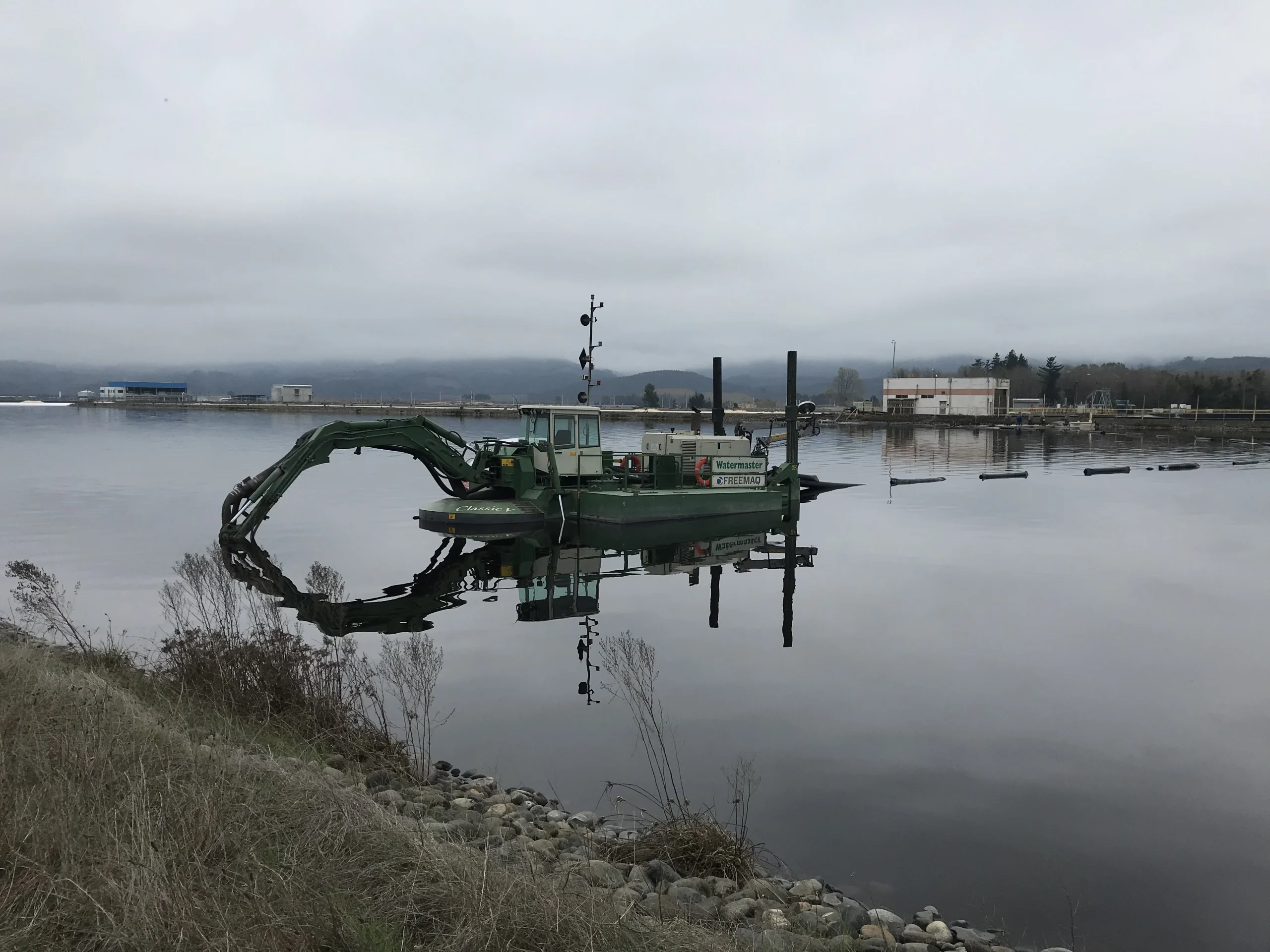 Equipo anfibio de dragado industrial operando en laguna para recuperación y manejo de sedimentos.