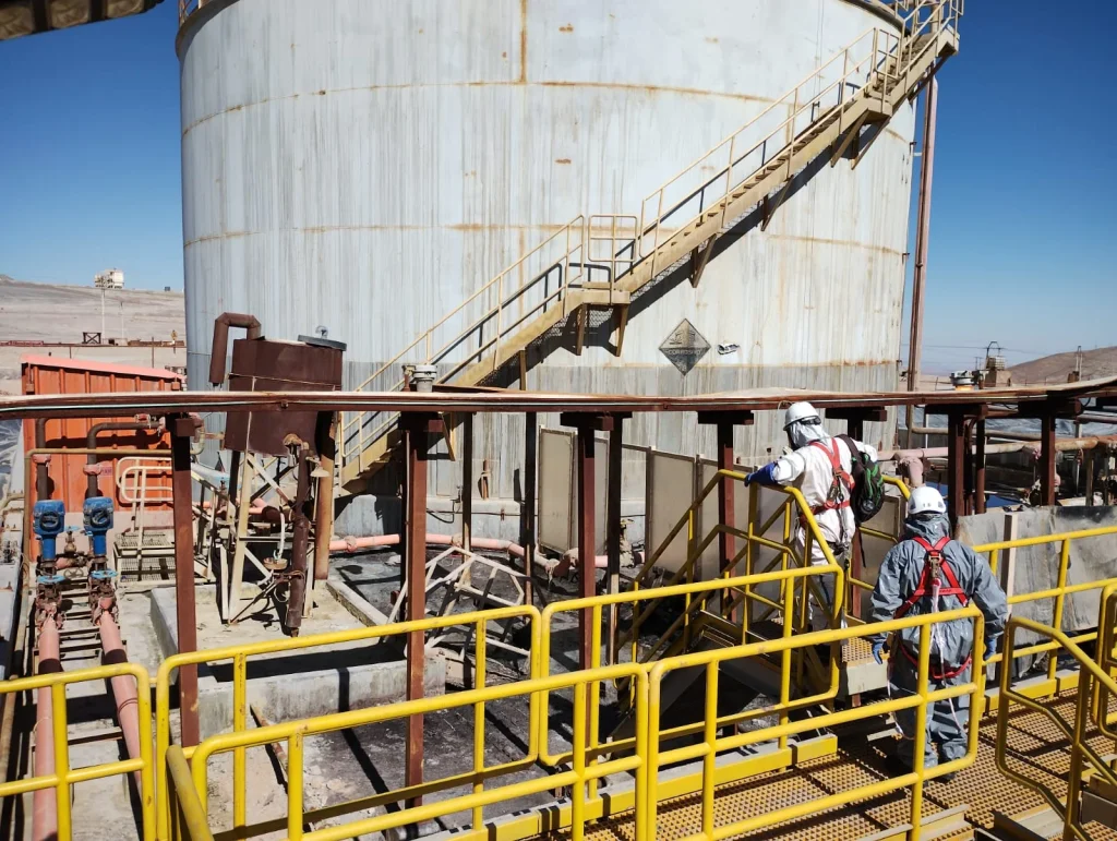 Trabajadores industriales realizando inspección y operación en planta minera con equipos de seguridad.