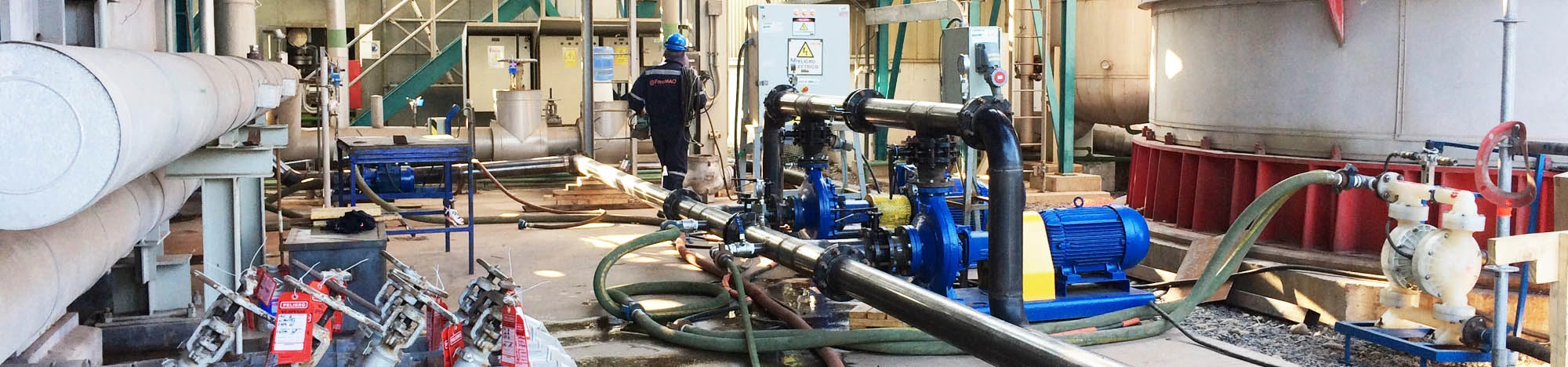 Sistema de tuberías y bombas industriales durante proceso de limpieza química en planta industrial.