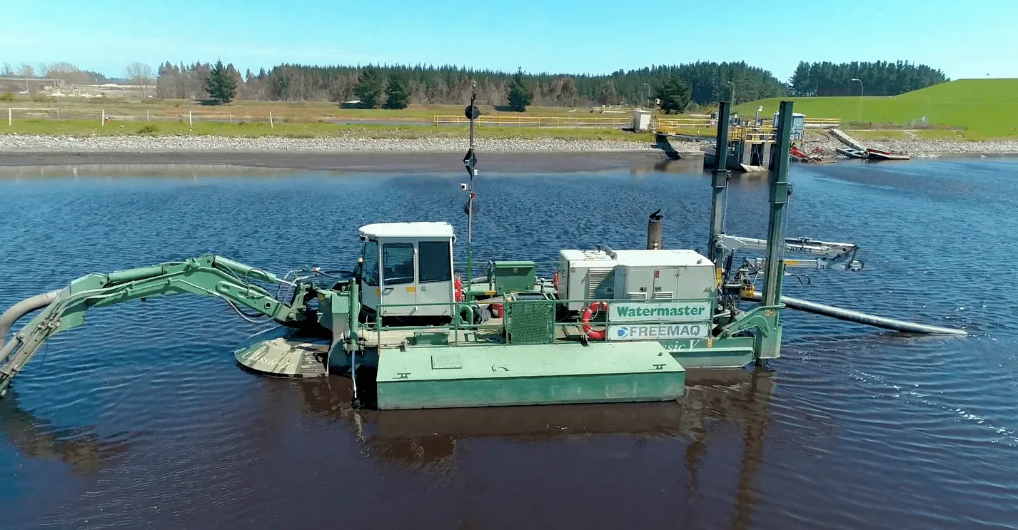 Draga anfibia Watermaster Classic V realizando trabajos de dragado y excavación en una laguna industrial con alta capacidad de bombeo y operación multipropósito.