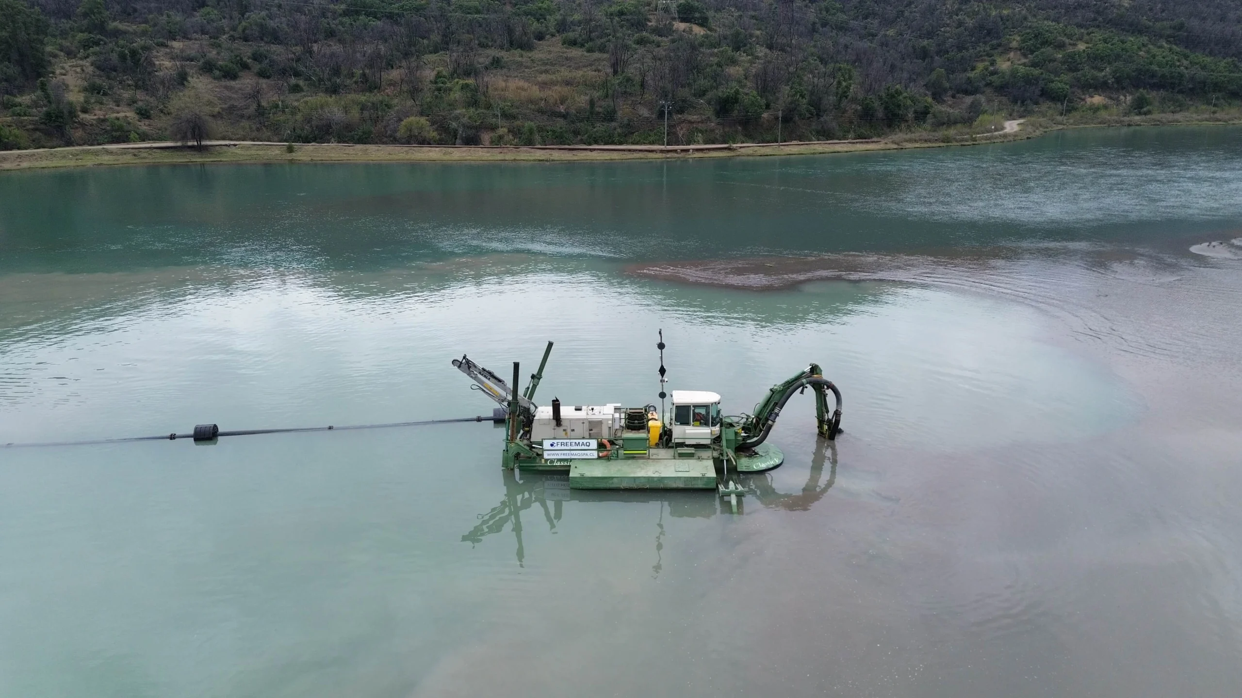 Draga Watermaster anfibia operando en una laguna industrial para la extracción de sedimentos, mantenimiento y recuperación de materiales.