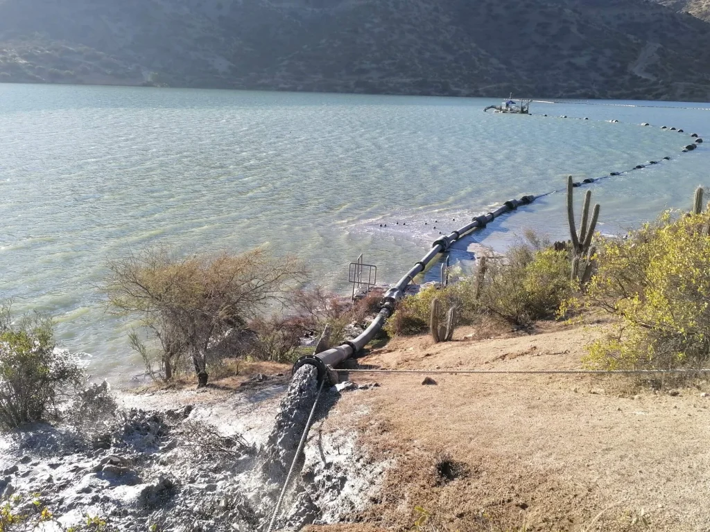 Tubería de descarga de relaves operando en un tranque minero para controlar flujos y optimizar la estabilidad de la infraestructura.