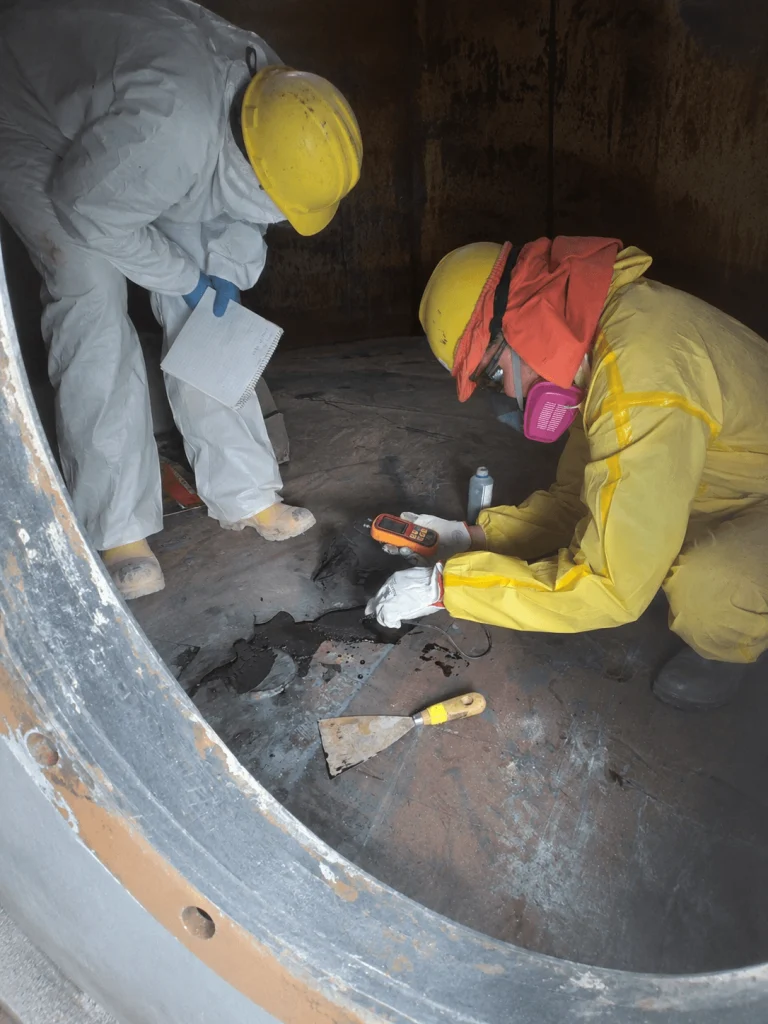 Profesional utilizando equipos de medición e inspección durante una evaluación técnica de ductos industriales en un espacio confinado.